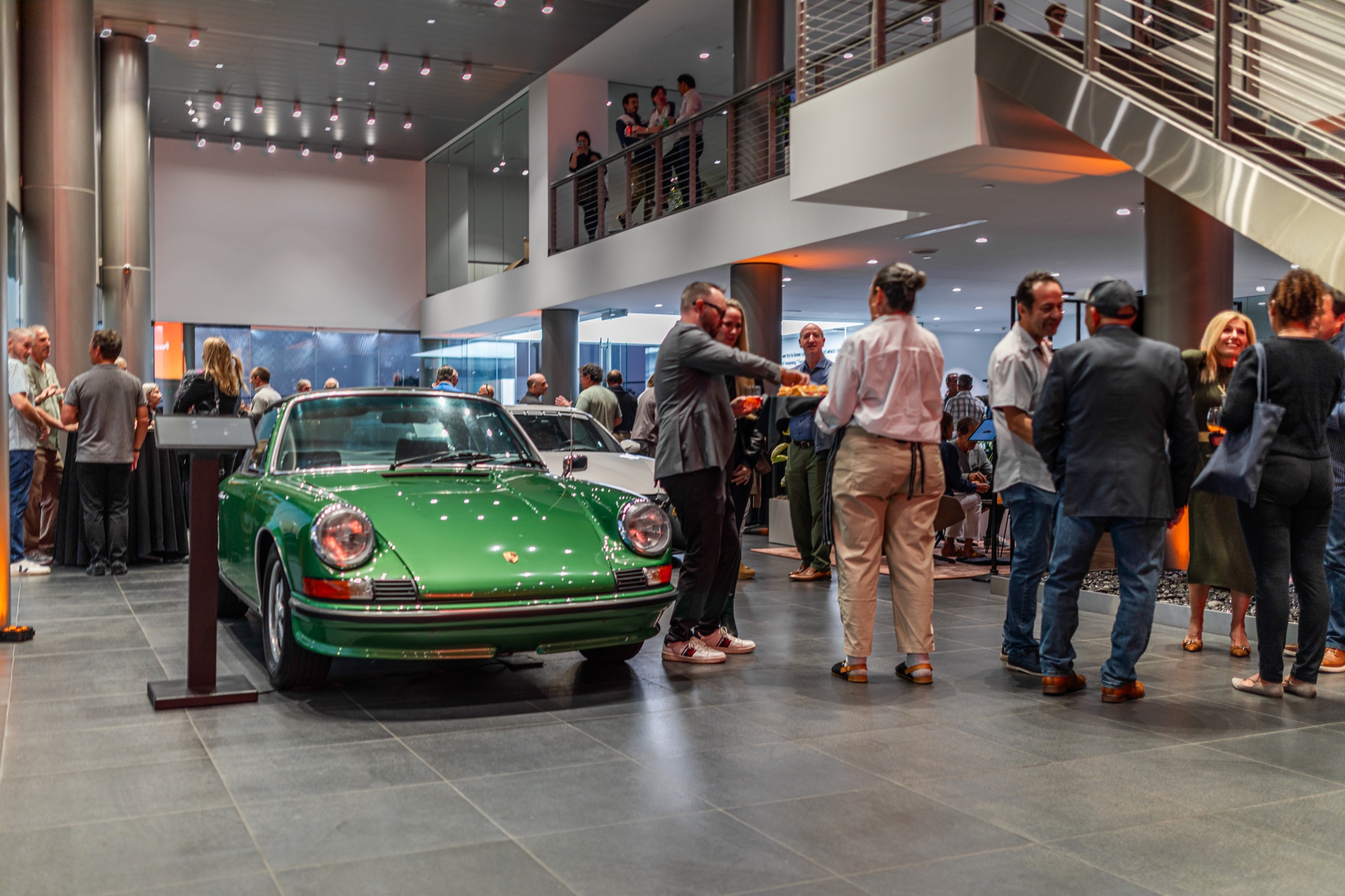 Guests gathered around a classic green 911 in the Porsche Carlsbad showroom during the Heritage and Horsepower event