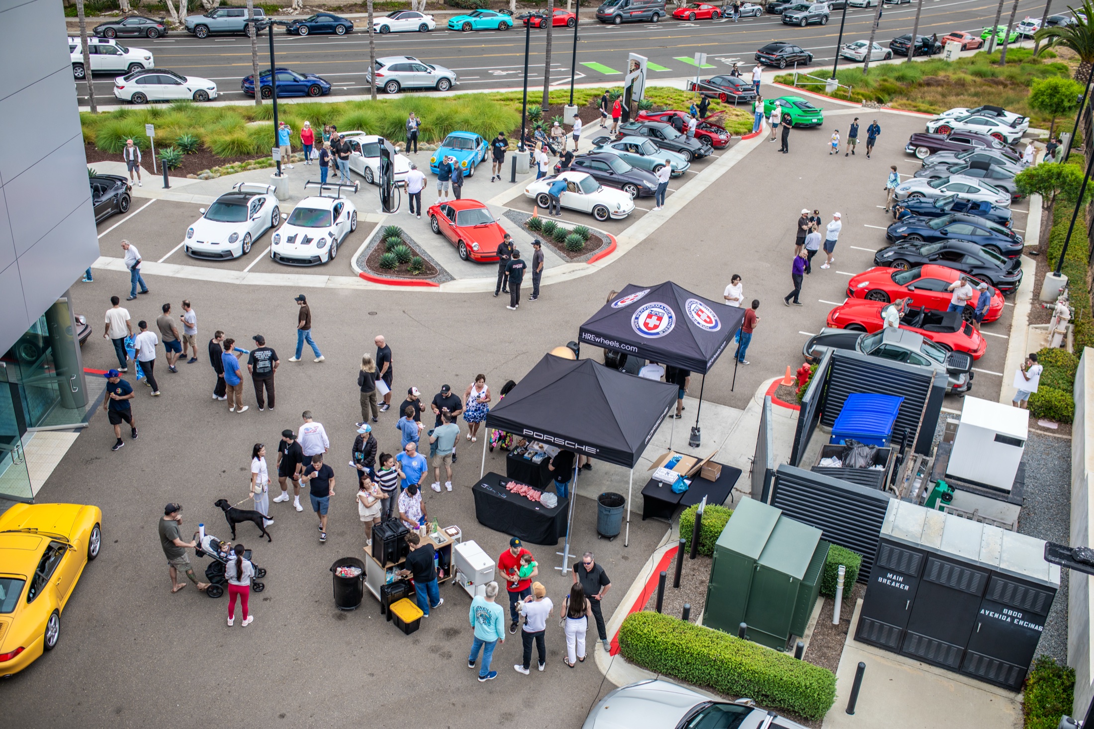 View from above of the Porsche Carlsbad lot with tents, cars, and visitors at the anniversary Cars and Coffee