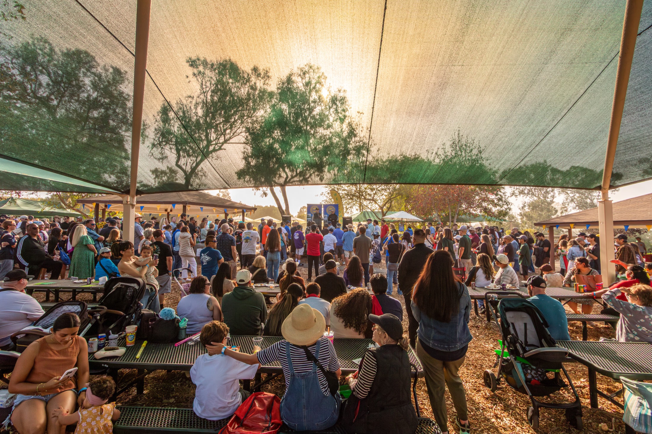 Employees and their families filling the picnic tables under the canopy at the 50th Anniversary picnic