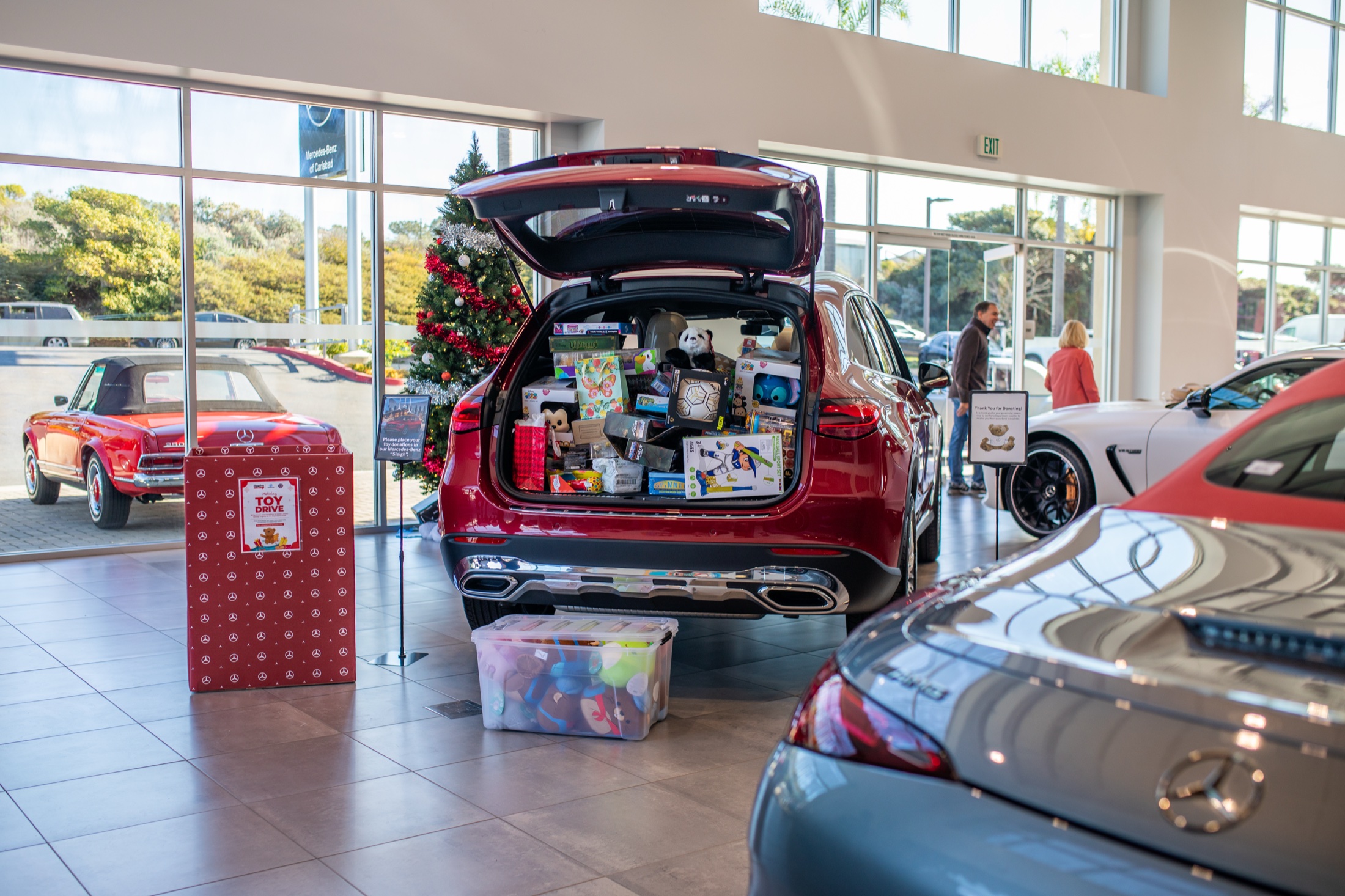 Red Mercedes SUV with its trunk full of donated toys in the Mercedes-Benz Carlsbad showroom