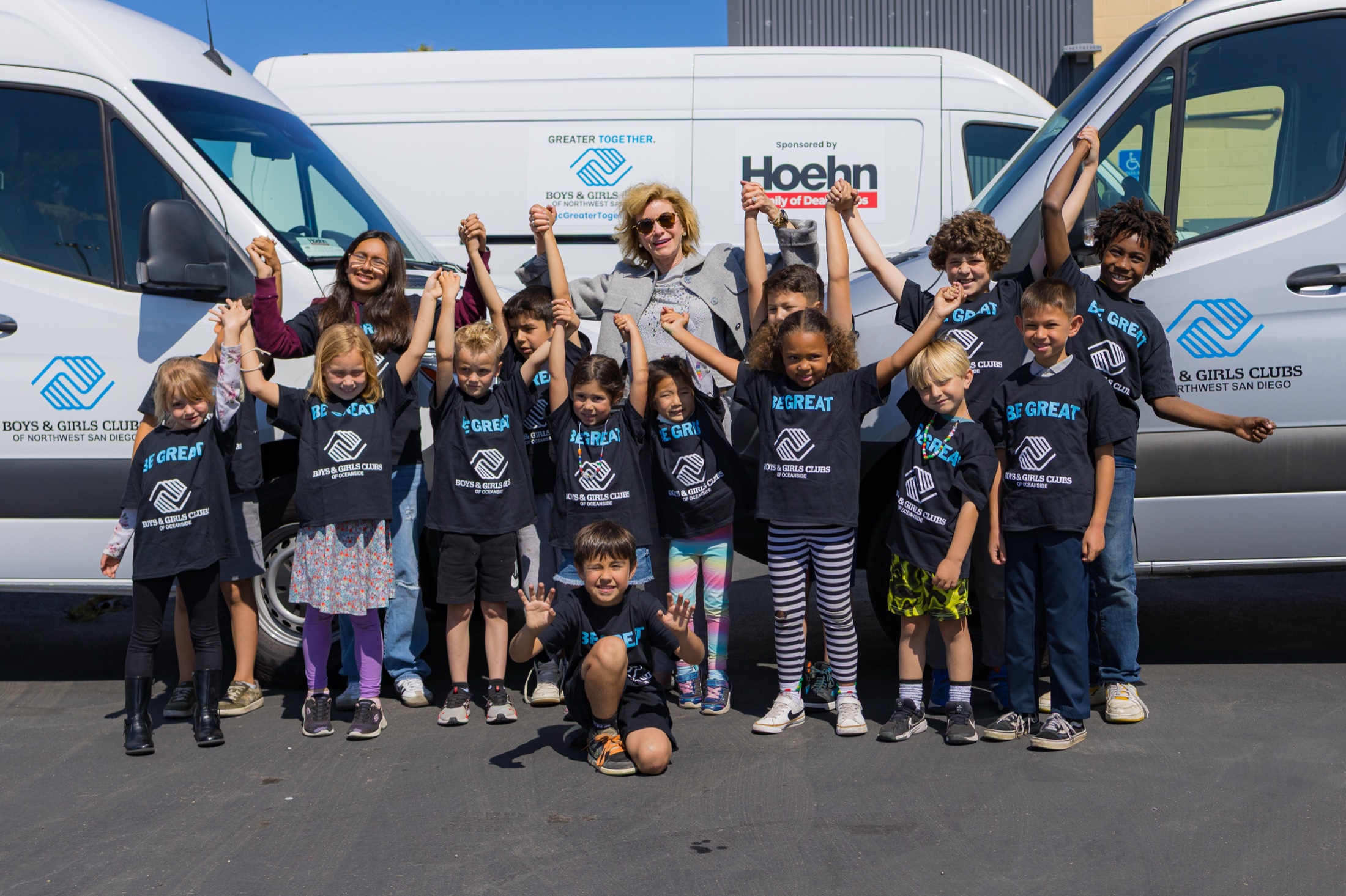 Children and staff in front of a Hoehn-branded Sprinter van at the donation handoff